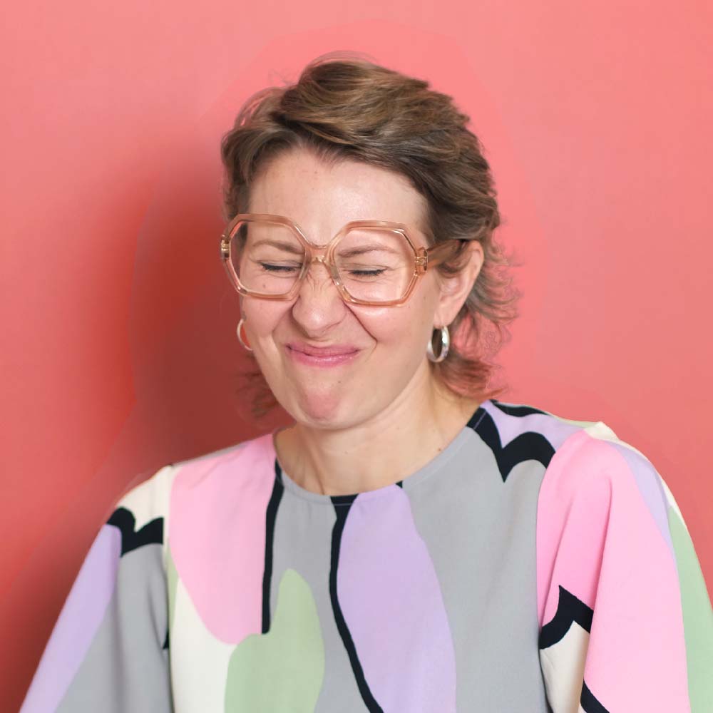 Porträt von Finja Trebesch, die eine Grimasse zieht und vor einem rotem Hintergrund sitzt.